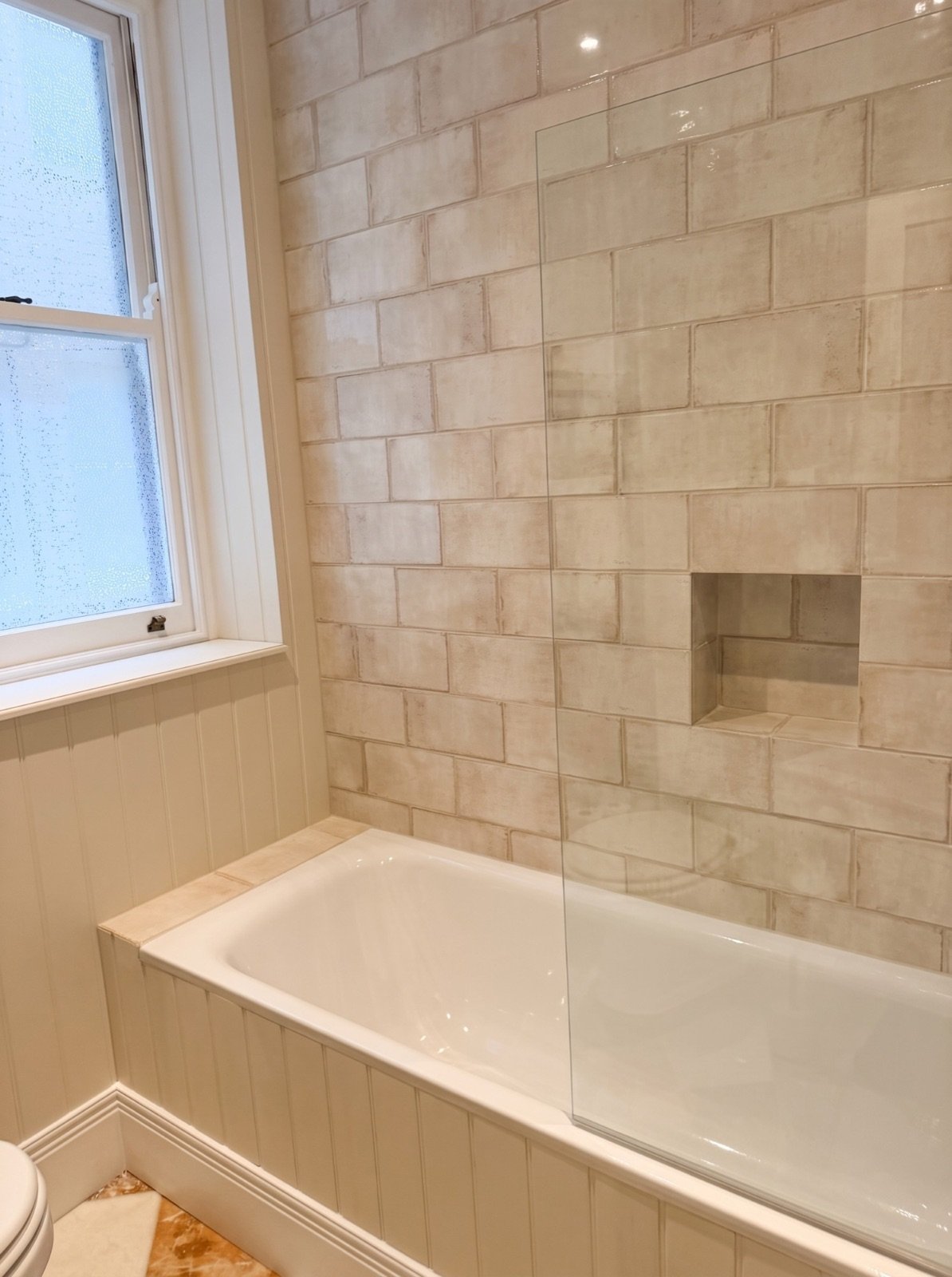 Bathroom with tiled walls, recessed niche, bath screen and tongue-and-groove panelling