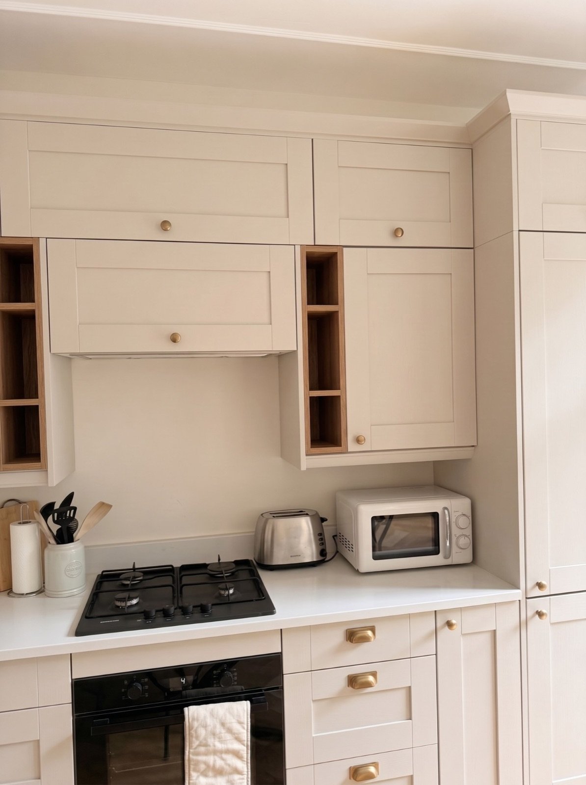 Shaker-style kitchen with brass handles, open oak shelving and gas hob
